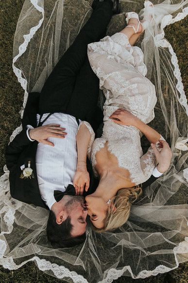 couple lay on bridal veil kissing romantically