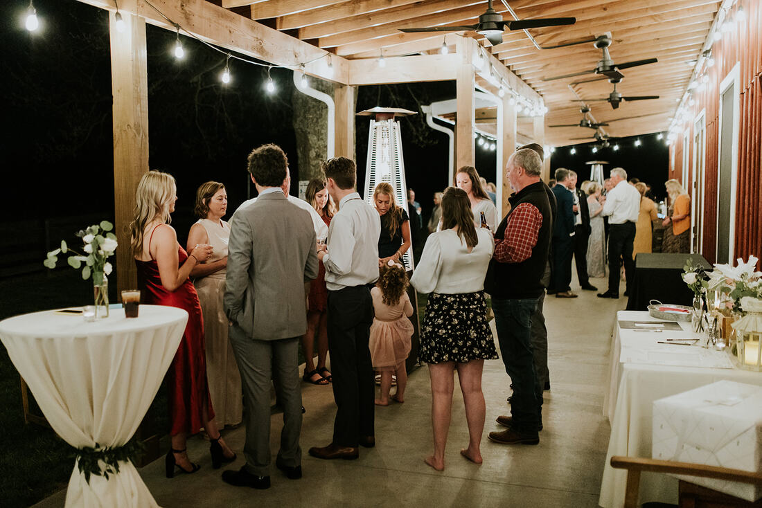 wedding guests relax on patio at barn wedding venue