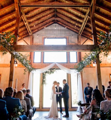 bride and groom kiss at indoor barn wedding ceremony
